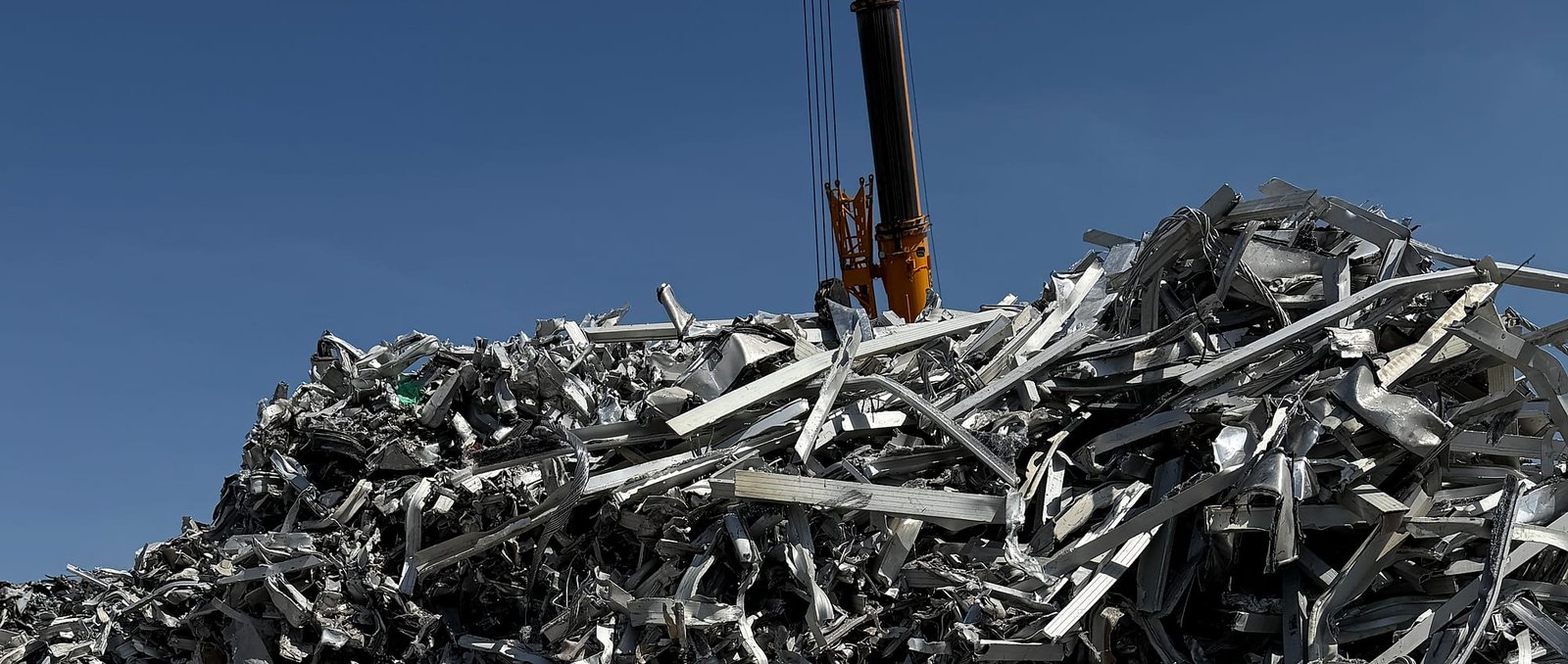 A grab crane working over a mountain of aluminium extrusion and shred